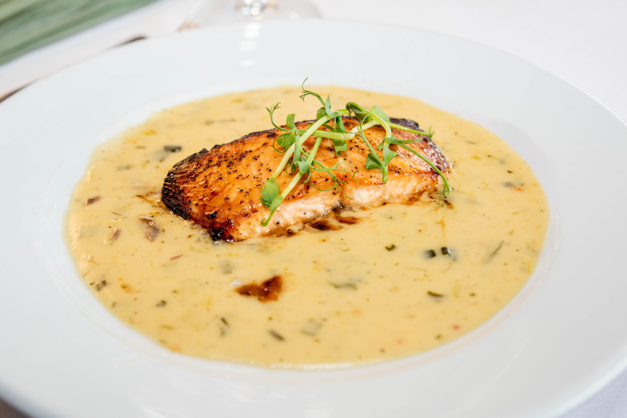 Salmon and sauce on a large white plate.