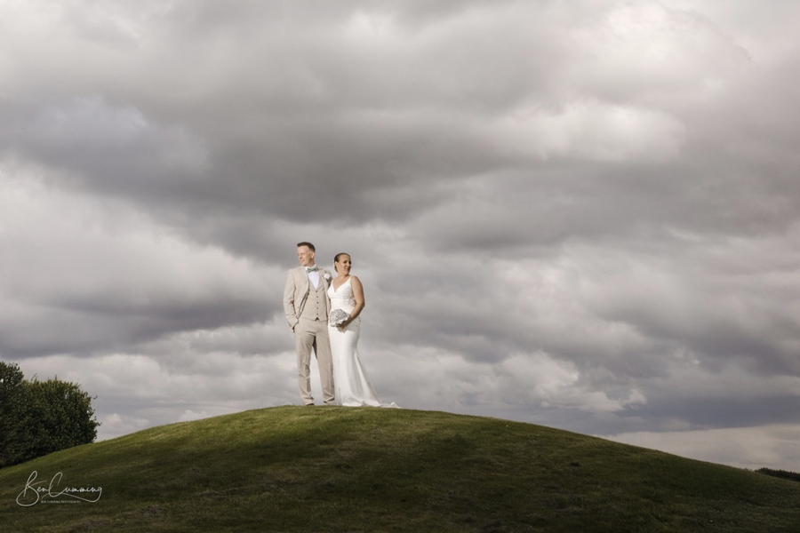 A bride and groom stand side-by-side beneath a moody sky at The Manor Leeds.