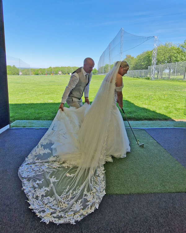 A bride and groom in The Manor's driving range, the bride is getting ready, the groom is behind her, arranging her dress.