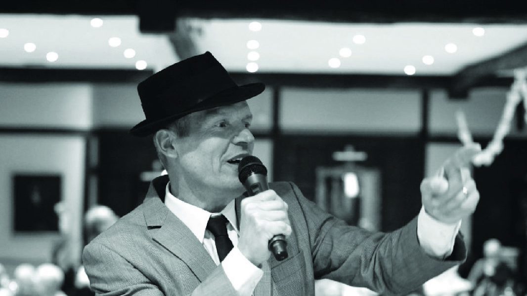 A black and white photo of Frank Sinatra tribute Phil Fryer singing into a microphone.