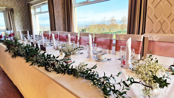 A long top-table set for a wedding breakfast in The View room of The Manor Leeds.