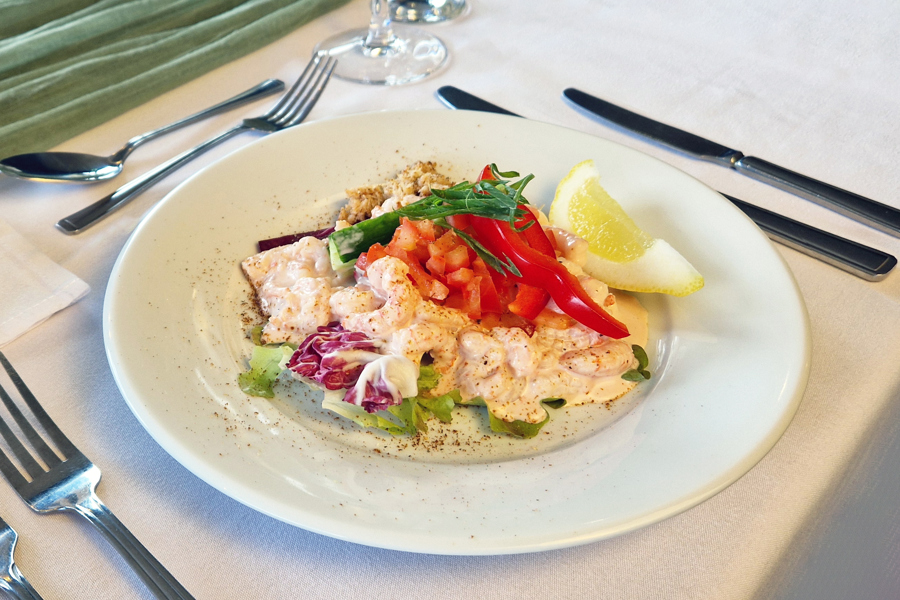 Prawn cocktail on a plate, placed on a formal dining table.