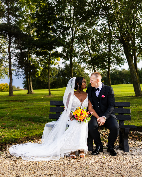 A bride and groom gaze at each other while sitting on a bench at The Manor Leeds.