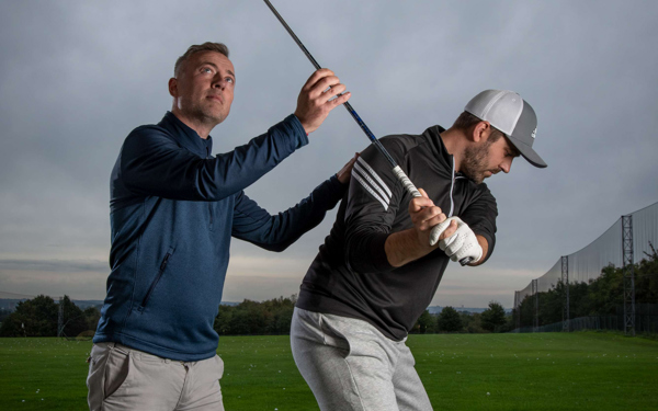 PGA Professional Richard Hedley and a golfer at The Manor's driving range, Richard is assessing the golfer's club.