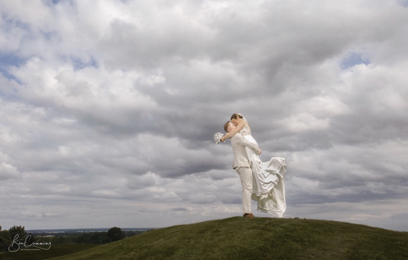 A groom lifts his bride beneath a moody sky at The Manor Leeds.