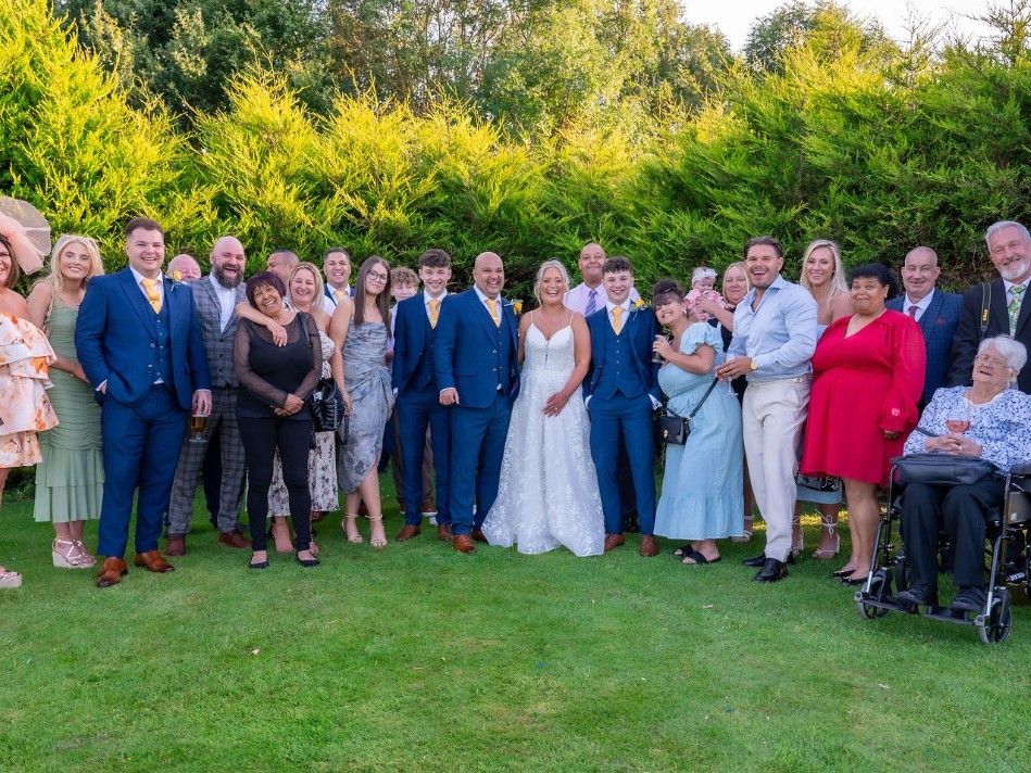 A bride and groom with their guests on The Lawn of The Manor.