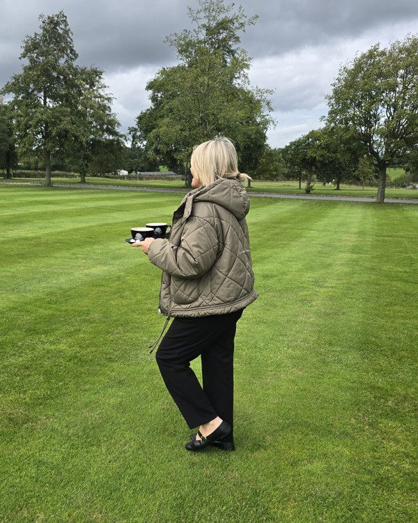 The Manor Events Manager Becky carrying coffee cups outside.