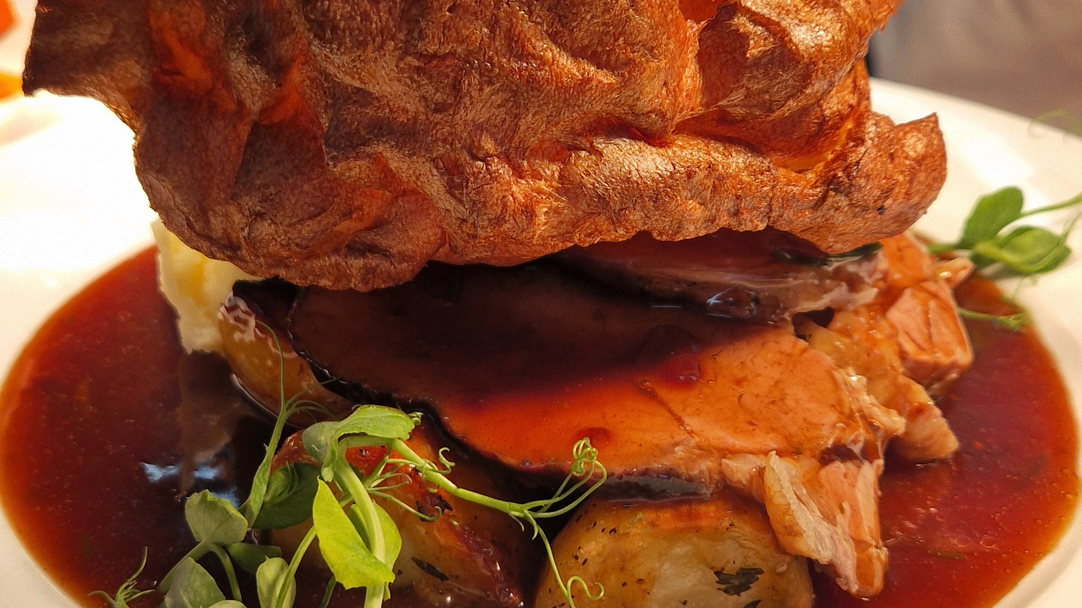 Roast dinner on a plate, Yorkshire Pudding, beef, roast potatoes and gravy.
