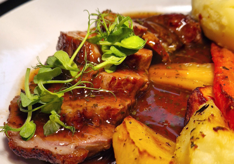 Roast lamb on a plate, with roast potatoes and minted gravy.