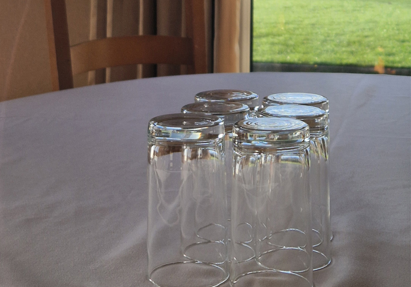 Six water glasses placed upturned on a table.